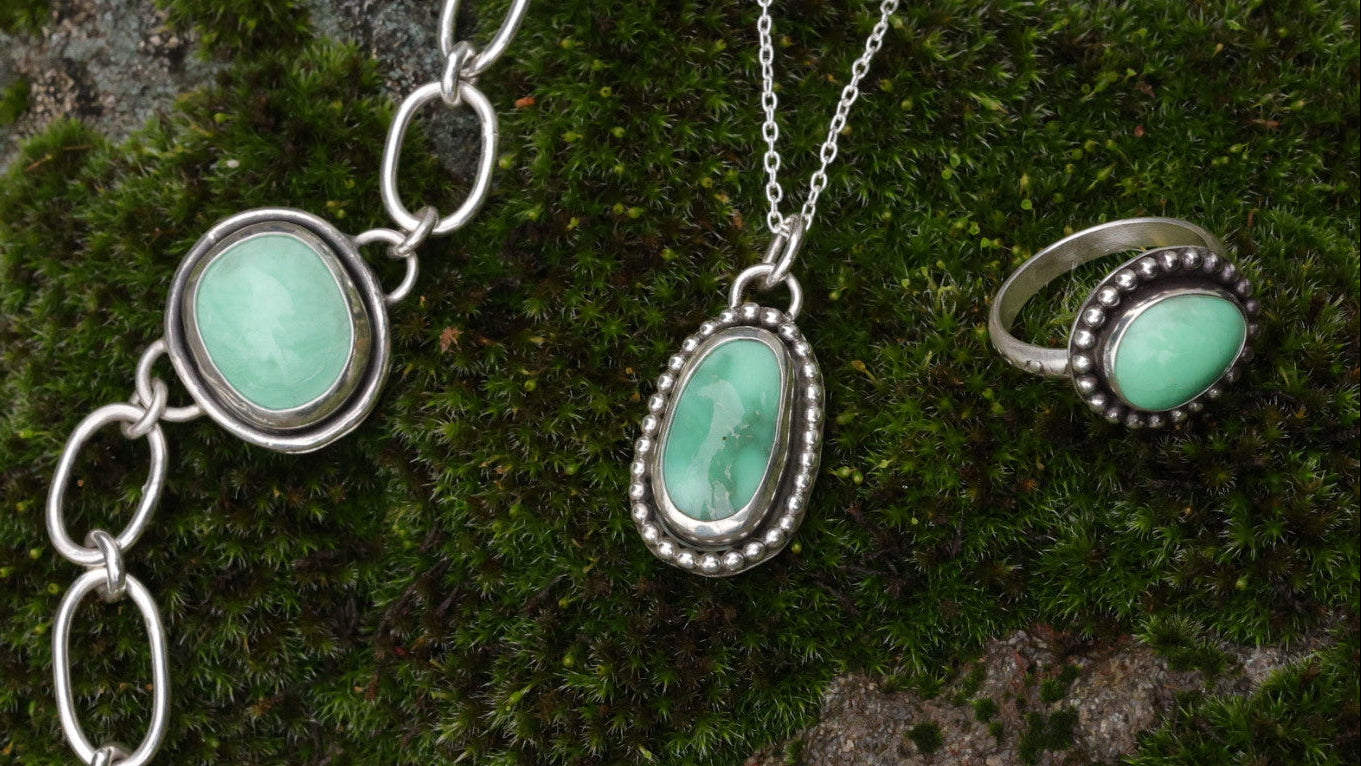 Jewelry set with turquoise stones and silver accents on a green moss background
